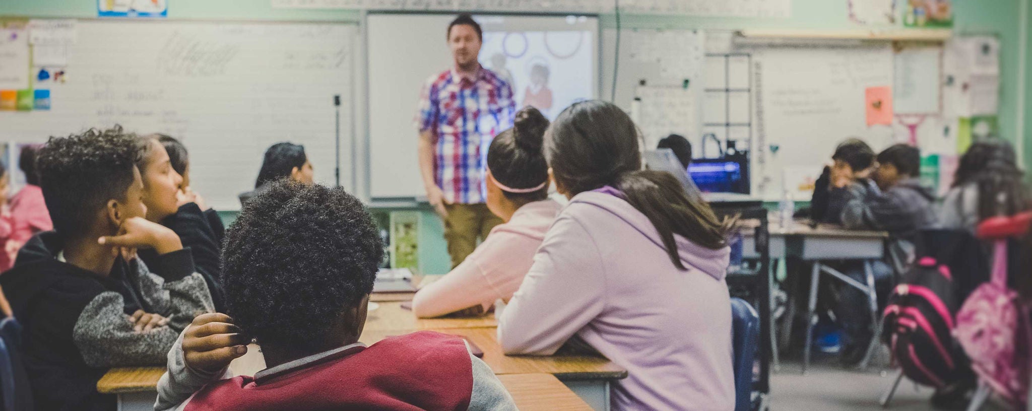 A classroom full of students listening to their teacher speak.