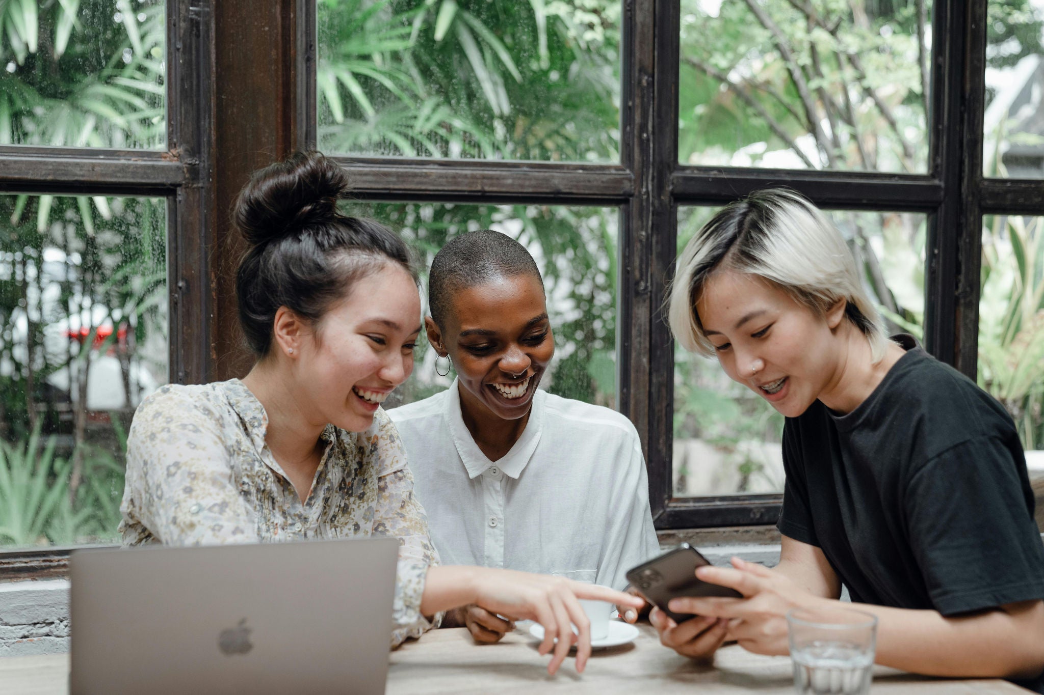 three women looking at computer and phone