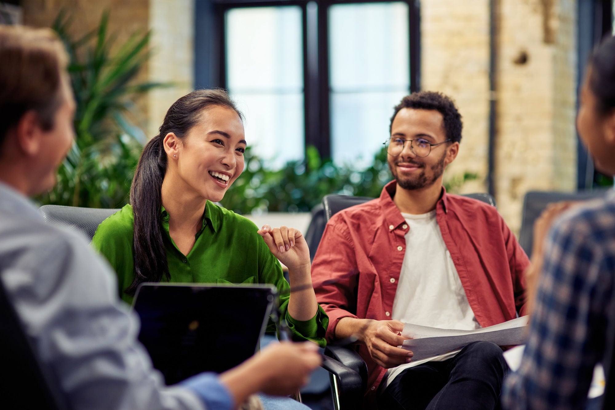 Young cheerful asian business woman discussing project results with colleagues while working together in the modern office. Teamwork and cooperation concept