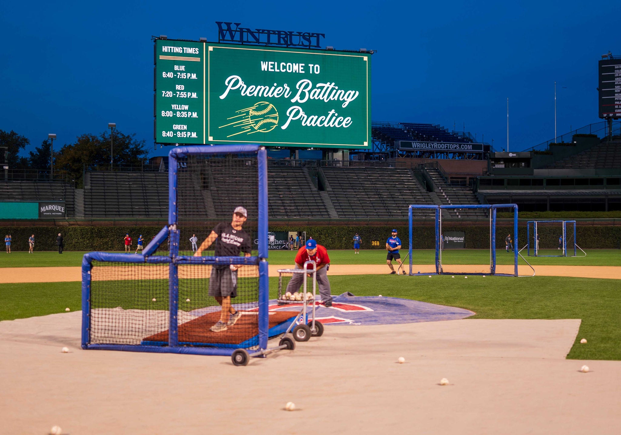 A baseball fan and a Slalom group, learning how to pitch at the annual Batting Practice at Wrigley Field.