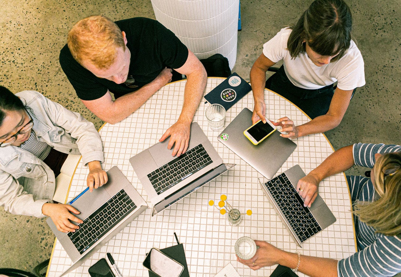 A group of employees working on laptops at a table.