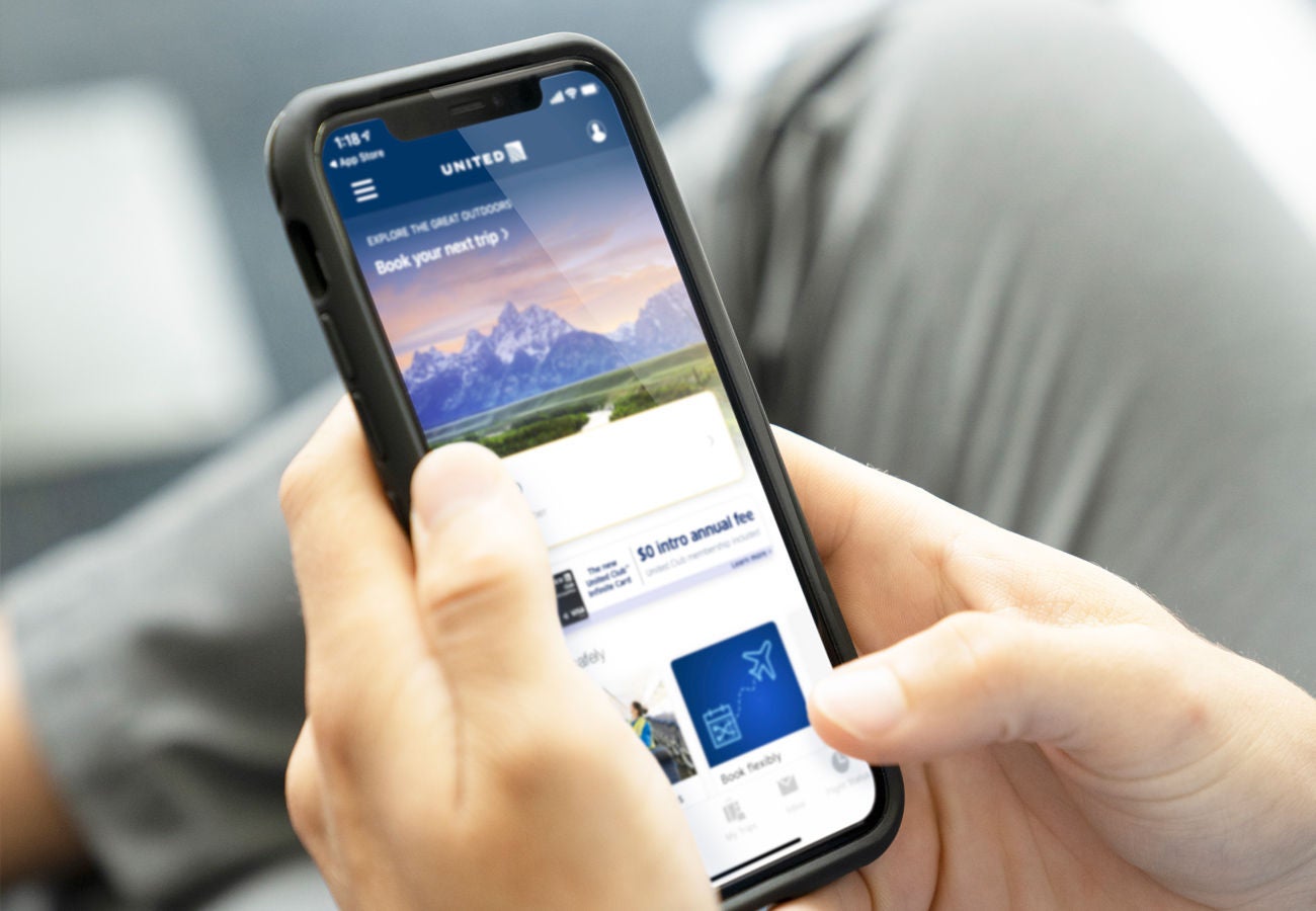 A person use their mobile device to explore the United Airlines app. 