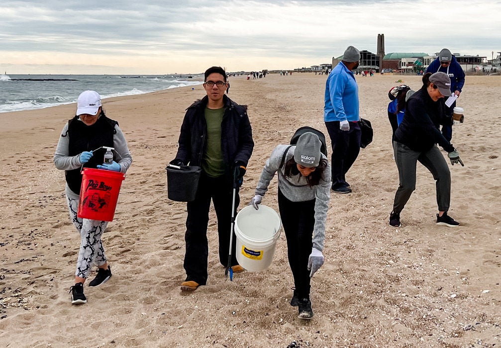 A team of Slalom employees work together to clean up a beach.