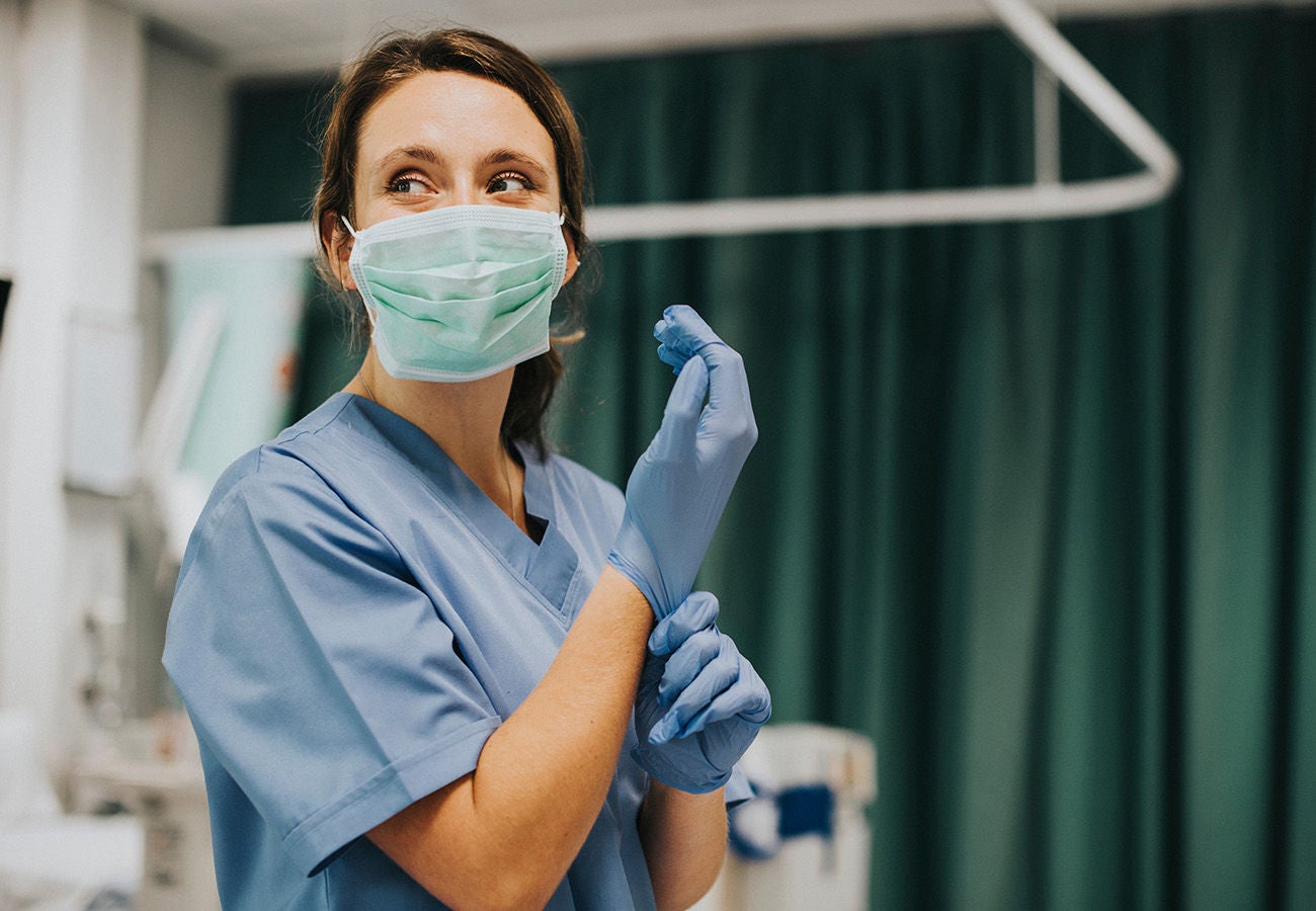 Nurse putting on gloves, preparing to treat a patient