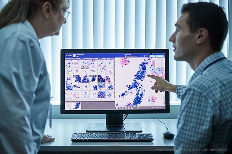 Two medical staff review a diagnostic image on a monitor. 