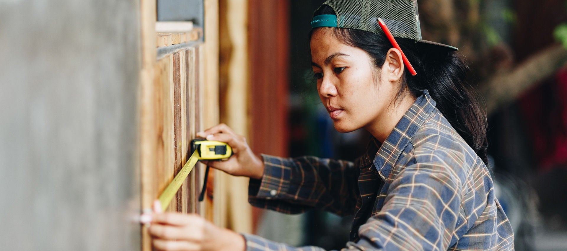 A woman is using a tape measure to measure a wall