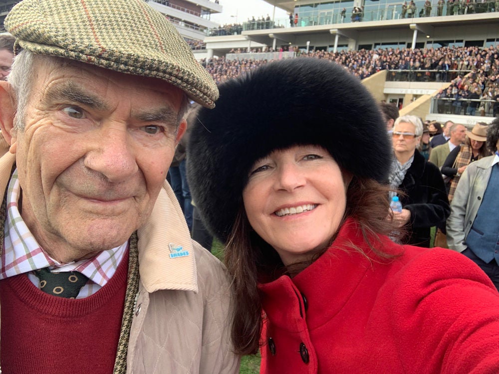 Ireland's general manager, Jane Dawson, at a stadium wearing a black fur hat and red jacket, smiling and standing next to a man in a tartan hat, red sweater, and tan jacket.