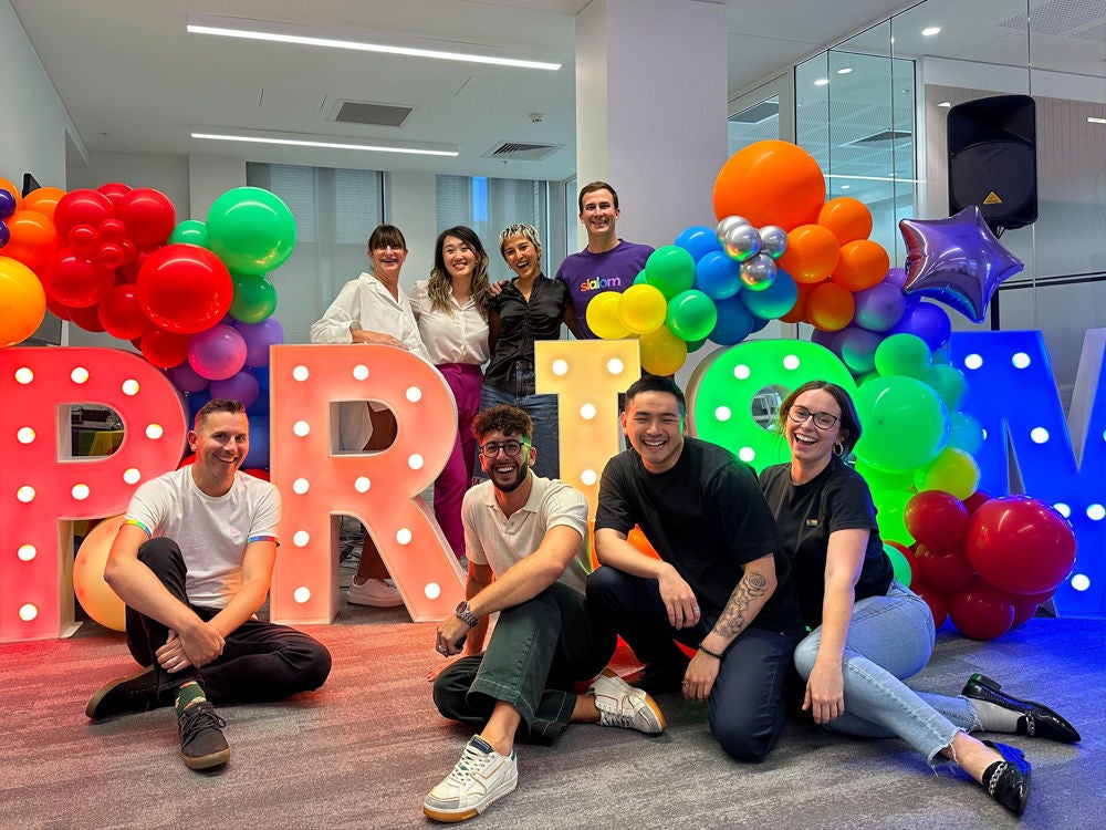 Slalom's employees snap a photo with large letetrs that spell Prism.