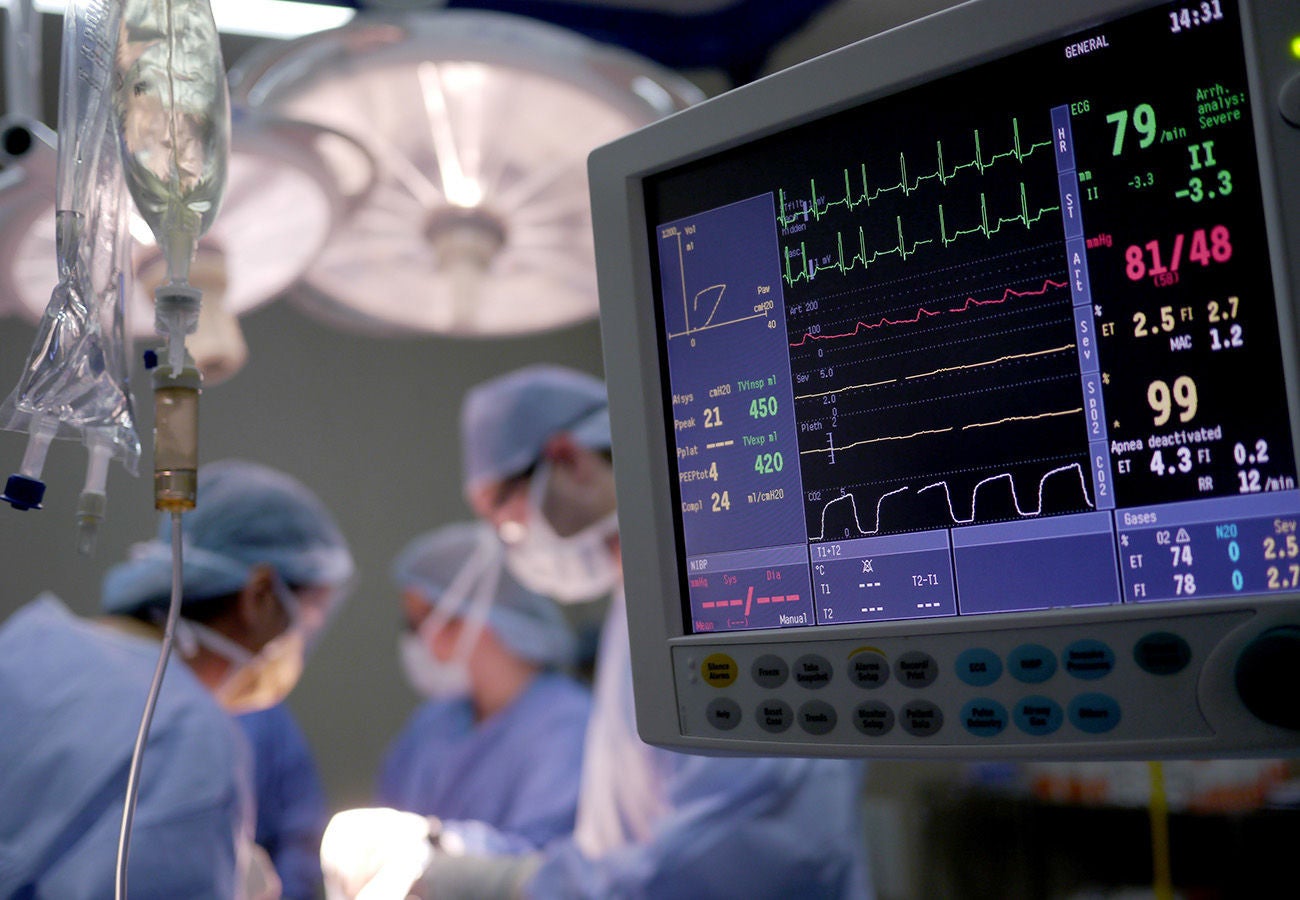 Doctors and nurses treating a patient as their vitals are displayed on a monitor