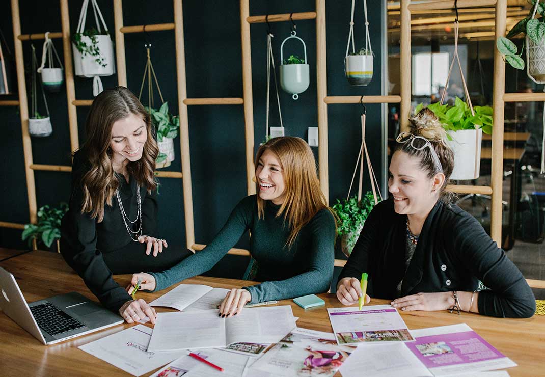 Three women having a meeting reviewing documents.